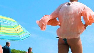 Playful nude beach girl caught on camera tanning